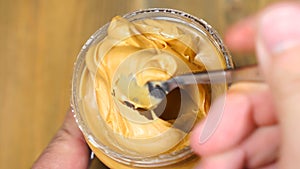 Mixing with a Spoon peanut butter. Creamy smooth peanut butter in jar backdrop