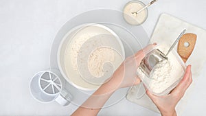 Mixing yeast starter and flour in a bowl. Step by step bread dough recipe, close up view from above