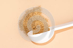 Mixture of biologically active additives for gut health. White scoop of dietary fiber on a beige background. Dietary herbal