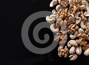 Mixture of nuts peanuts, pistachios, almonds, walnuts, hazelnut, cashew from top view with black background with copy space