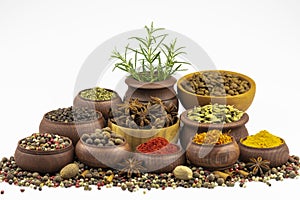 A mixture of peppers scattered among the spices in a wooden bowl isolated on a white background