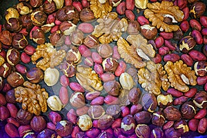 A mixture of roasted walnuts, hazelnuts and peanuts in a pan close-up.