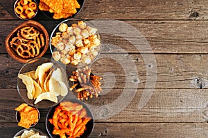 Mixture of salty snacks, above view side border on a wood background