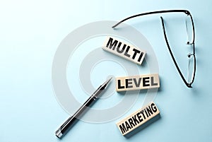 MLM - multi level marketing text on wooden block ,blue background