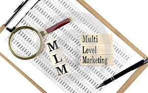 MLM - multi level marketing text on wooden block on chart background