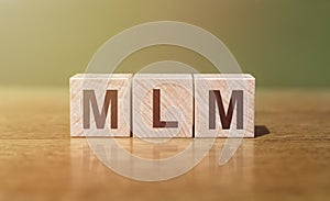 MLM Multi-Level Marketing word written on wooden blocks on wooden table. Concept for your design