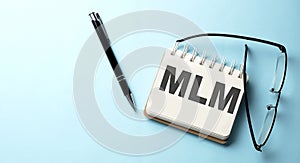 MLM text is written on a notepad on the blue background