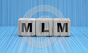 MLM - word on wooden cubes on a beautiful blue background