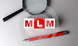 MLM word on wooden cubes with pen and magnifier