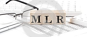 MLR - Minimum Loan Rate written on wooden cube with keyboard , calculator, chart,glasses.Business concept