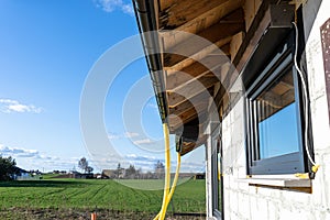 100mm diameter yellow PVC pipe connected to the end of the gutter on the roof, protected against water. photo