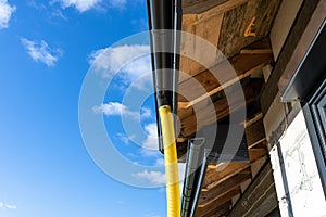 100mm diameter yellow PVC pipe connected to the end of the gutter on the roof, protected against water. photo
