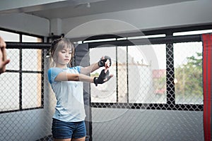 An MMA female athlete does an extended arm wand wrist stretch as she in the ring cage for her vigorous training