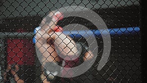 MMA fighters spar in boxing cage, blurred. Athletes in octagonal ring for fights