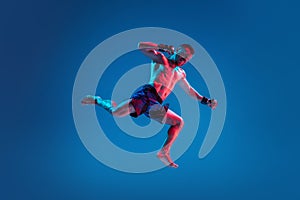 MMA. Professional fighter punching or boxing isolated on blue studio background in neon