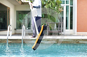 Mna is cleaning a swimming pool with a brush