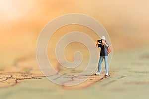 Mniature people: Photographers travel on the world map, take photos everywhere.