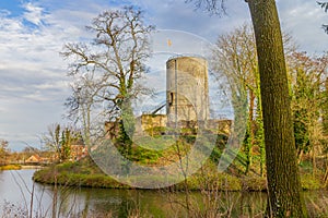 Moat with calm water with the tower of the Stein castle ruins on a hill, bare trees, climbing plants