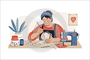 A person in a red shirt and black apron is painting a ceramic pot at a craft table