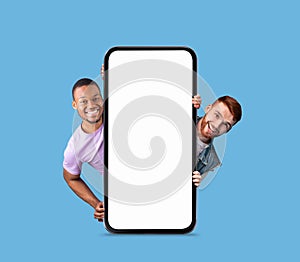 Mobile Ad. Two Cheerful Men Peeking Out Behind Big Blank Smartphone