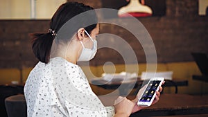 Mobile application, smartphone app with menu. Woman, in protective mask, uses an application on smartphone to place an