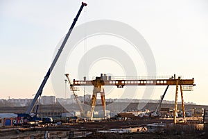 Mobile auto cranes and gantry crane working at construction site.