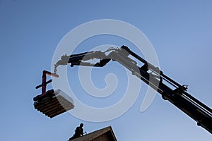 Mobile boom truck forklift delivering materials to rooftop