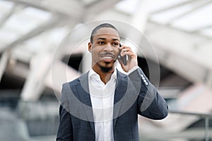 Mobile Call. Portrait Of Young Black Businessman Talking On Cellphone At Airport