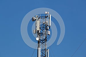 Mobile cell phone tower against the background of a blue sky and white cloud. Telecommunication TV tower. Cellular antenna. Wi-fi