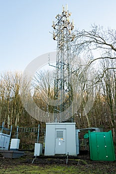 Mobile cell phone transmitter tower a woodland in winter sunlight