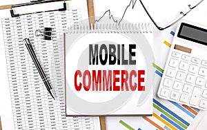 MOBILE COMMERCE text on notebook with chart, calculator and pen