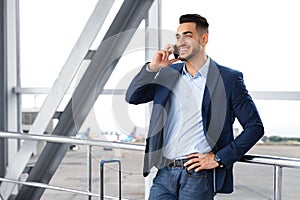 Mobile Communication. Handsome Middle Eastern Man Talking On Cellphone In Airport
