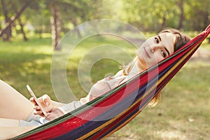 Mobile communications and summer holidays, a young girl in a hammock with a smartphone