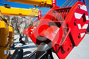 Mobile construction cranes with yellow telescopic arms and big tower cranes in sunny day