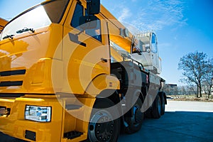 Mobile construction cranes with yellow telescopic arms and big tower cranes in sunny day