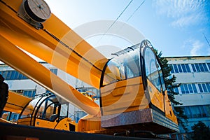 Mobile construction cranes with yellow telescopic arms and big tower cranes in sunny day