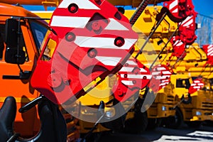 Mobile construction cranes with yellow telescopic arms and big tower cranes in sunny day