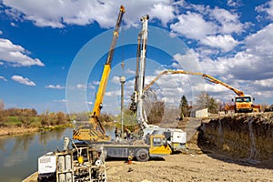 Mobile crane and truck pump pouring fresh concrete into bridge foundation