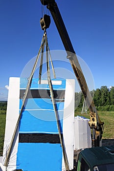 The mobile crane unloads pallets of blocks from the trailer of the truck