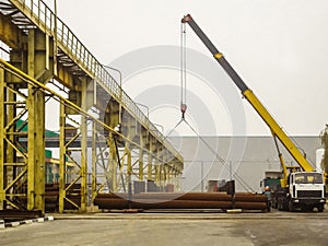 Mobile crane unloads steel pipes