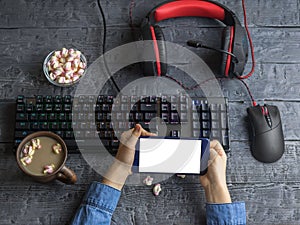 Mobile device in the hands of a child on a background of Desk with computer facilities. Clipping background.