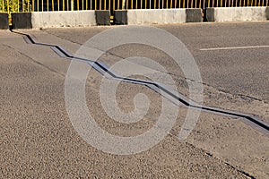 Mobile drainage connection on the carriageway of the bridge. Metallic zigzag edge of drainage channel on asphalt