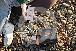 Mobile in hand connected to portable power station via cord