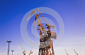 Mobile harbor cranes over blue sky. Transport and technology concept