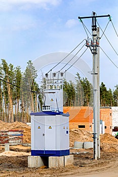 A mobile live transformer booth stands near high voltage poles on a construction site