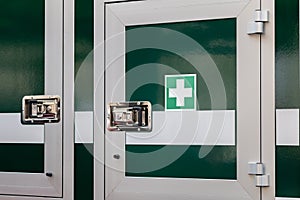 Mobile medkit compartment locked door on a vehicle with a green white cross symbol, professional first aid medical kit locker,