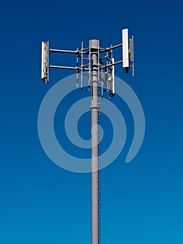 Mobile phone antennas on metal tower on blue sky