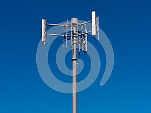 Mobile phone antennas on metal tower on blue sky