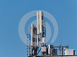 Mobile phone base station  atop of a building against a blue sky on a sunny day