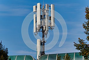 Mobile phone base station atop of a building against a blue sky on a sunny day